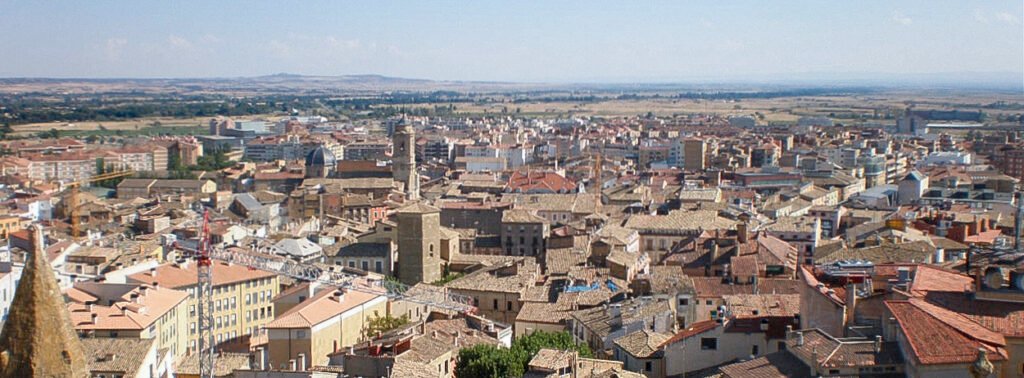 Paisaje urbano de Huesca con arquitectura tradicional y fondo montañoso, representativo del entorno histórico y natural de la provincia.